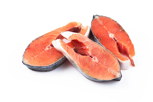 Three fresh salmon steaks arranged on a white background. The vibrant orange flesh contrasts with the dark skin, conveying freshness and quality.